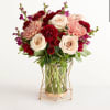 Bouquet of cream roses, pink mums, and red carnations in a glass vase