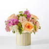 Peach and pink flower arrangement in a ribbed cream vase