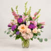 Mixed pink and purple flowers arranged in a clear glass vase