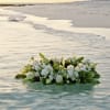 White floral arrangement floating on water at the beach