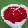 Bouquet of red roses wrapped in white paper with a pearl ribbon