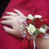 Red and white rose wrist corsage on a hand