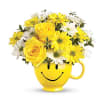 Yellow and white flowers arranged in a smiley-face mug