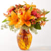 Orange lilies and roses in an amber glass vase