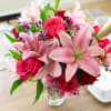 Pink lilies and red roses arranged in a clear glass vase