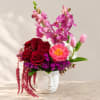 Mixed bouquet in a white face vase with pink orchids, red roses, and tulips