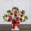 Large red and white floral arrangement with lilies and roses in a white container
