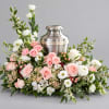 Pink and white floral arrangement around a silver urn