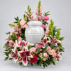 Pink and white floral arrangement surrounding a white urn
