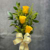 Three yellow roses with greenery and a striped ribbon bow
