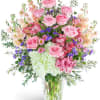 Pink roses and mixed flowers arranged in a clear glass vase