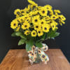 Yellow daisy bouquet in a glass vase with a sunflower-patterned ribbon