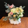 Floral arrangement in a white pumpkin-shaped vase with pink and cream blooms