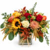 Autumn bouquet with roses, sunflower, chrysanthemum, and a glass vase