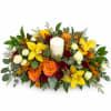 Yellow orchids and roses arranged around a white pillar candle