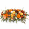 Low floral centerpiece with orange pumpkins and roses in autumn colors