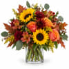 Bouquet of sunflowers, roses, and autumn flowers in a clear glass vase
