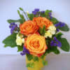 Orange roses with purple filler flowers in a yellow vase