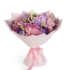 Bouquet of pink, purple, and lavender flowers wrapped in pale pink paper