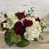 Red roses and white hydrangeas in a green glass vase