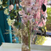Pink orchids arranged in a tall glass vase with decorative branches