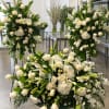 Large white floral funeral arrangements with roses and lilies in a room