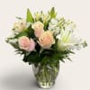 Pink roses and white lilies arranged in a clear glass vase