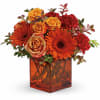 Orange and red flowers arranged in a square amber vase