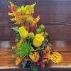 Yellow roses and green pom flowers with autumn leaves and a pumpkin accent
