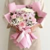 Pink-wrapped bouquet of pastel chrysanthemums with a white ribbon