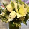 A GLASS CUBE FILLED WITH WHITE ROSES, WHITE LILLIES, ASTERS, WHITE DAISIES
