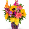 Colorful bouquet with sunflowers, pink carnations, and snapdragons in a purple vase