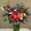 Colorful mixed bouquet in a tall green glass vase
