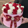 Red and white roses in a pink round box with a heart ribbon