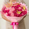 Pink and magenta rose bouquet wrapped in pink paper with gold crown and butterfly picks