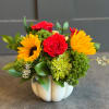 Red roses and yellow sunflowers in a white pumpkin vase
