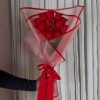 Bouquet of red roses wrapped in pink translucent paper with a red ribbon