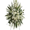 White floral standing spray on an easel with lilies and roses