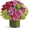 Pink roses and tulips arranged in a green glass vase
