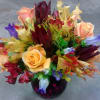 Bouquet of multicolored roses and tropical flowers in a dark vase