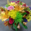 Colorful mixed bouquet with roses, lilies, and daisies in a glass vase