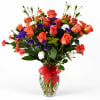 Bouquet of orange roses, purple statice, and white carnations in a glass vase