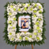 White and lime green funeral wreath around a framed photo on an easel