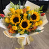 Bouquet of yellow roses and sunflowers with red tulips in cream wrap