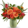 Orange roses and red alstroemeria in a green ceramic pitcher