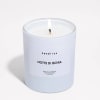 Lit white scented candle in a frosted glass jar