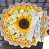Round bouquet of yellow and cream roses with a sunflower center and white ribbon