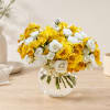 Yellow and white roses arranged in a clear glass bowl vase