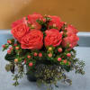 Pink roses arranged in a low vase with berry-like accents