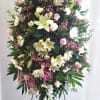 Tall standing floral spray with pink and white flowers on a black easel
